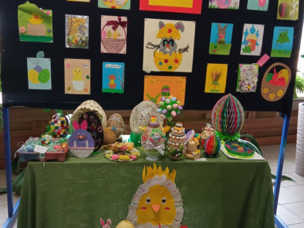 Stolik i gazetka ze świątecznymi ozdobami. Modele jajek i świąteczne kartki wykonane przez dzieci