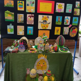 Stolik i gazetka ze świątecznymi ozdobami. Modele jajek i świąteczne kartki wykonane przez dzieci